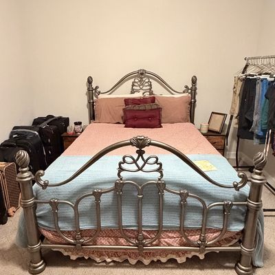 Sale Photo Thumbnail #227: Traditional pewter-finish metal bed frame featuring scrollwork detailing and decorative finials, complete with mattress and bedding.