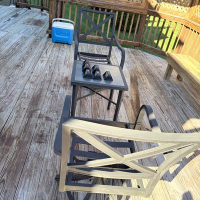 Sale Photo Thumbnail #96: Black metal patio set featuring two swivel chairs with X-back designs and a small square side table, arranged on a wooden deck alongside a blue Igloo cooler.