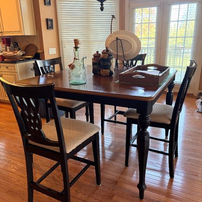 Sale Photo Thumbnail #143: Counter-height dining table featuring a wood top, black legs, and four matching high-back chairs with lattice cutouts and upholstered seats.