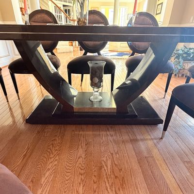 Sale Photo Thumbnail #110: Contemporary dining table featuring a high-gloss black finish, sculptural pedestal base with metallic accents, and coordinating oval-back upholstered chairs.