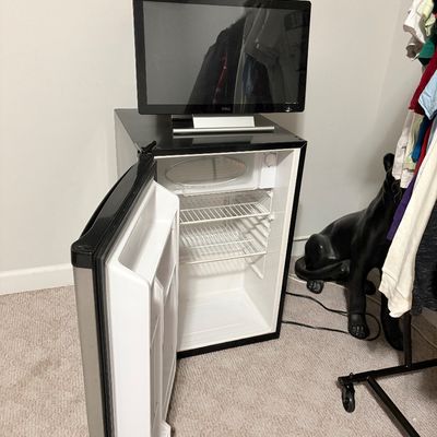 Sale Photo Thumbnail #234: Compact black mini refrigerator with open door showing interior wire shelves, paired with a flat-screen Dell computer monitor resting on top.