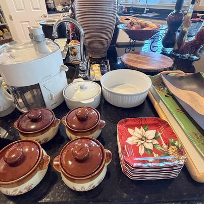 Sale Photo Thumbnail #99: Collection of kitchen and dining items, featuring a white electric juicer, four ceramic lidded onion soup bowls, a stack of festive poinsettia dessert plates, and a tall striped ceramic vase.