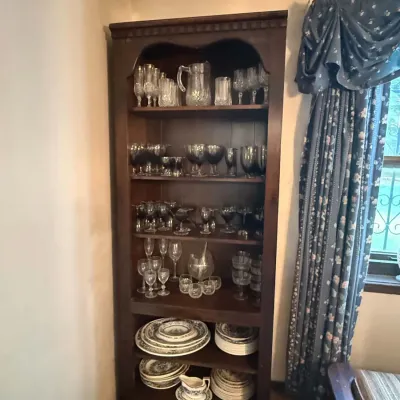 Sale Photo Thumbnail #39: Tall, dark wood open hutch filled with crystal glassware, stemware, decanters, and a set of floral pattern china.