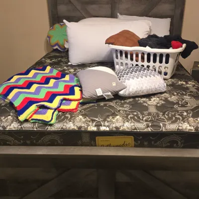 Sale Photo Thumbnail #28: Rustic modern grey wood-look bed frame with X-brace panel details, featuring a mattress layered with a colorful crocheted chevron throw, pillows, and a laundry basket.