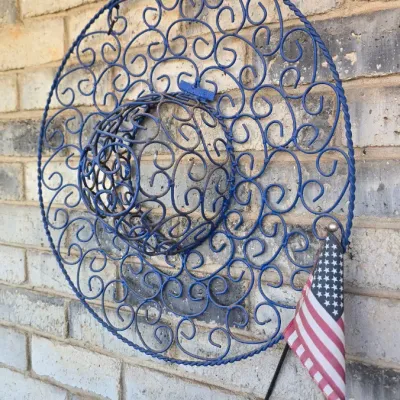 Sale Photo Thumbnail #69: Blue painted wrought iron hat-shaped hanging planter or wall decor with intricate scrollwork and a small American flag attachment.
