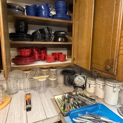 Sale Photo Thumbnail #31: Open kitchen cabinet filled with colorful solid ceramic dishware, accompanied by countertop canisters, clear storage jars, and trays of utensils.
