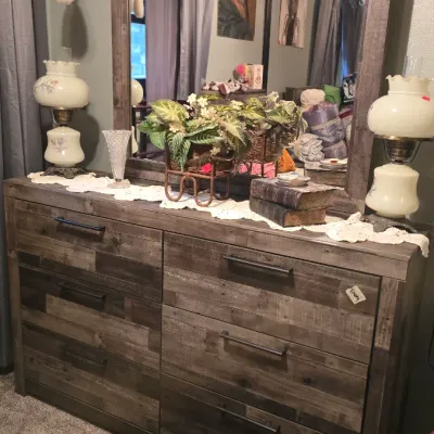Sale Photo Thumbnail #13: Rustic rustic-finished wooden six-drawer dresser with matching framed mirror, flanked by two vintage floral hurricane lamps.