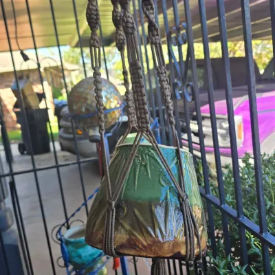 Sale Photo Thumbnail #67: Vintage 1970s macramé plant hanger featuring brown woven cord with wooden beads and a bottom tassel, holding a glazed ceramic planter.