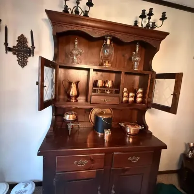 Sale Photo Thumbnail #43: Rustic dark wood hutch and buffet featuring leaded glass cabinet doors, displayed with various copper and glass serving pieces.