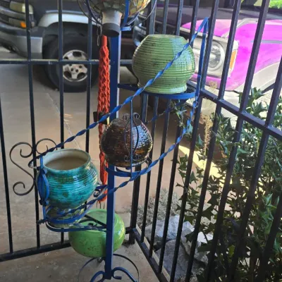 Sale Photo Thumbnail #68: Blue wrought-iron spiral plant stand holding assorted ceramic pots and a glass mosaic gazing ball ornament.