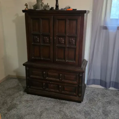 Sale Photo Thumbnail #59: Dark stain Spanish Revival armoire featuring carved floral panel doors and two lower drawers.
