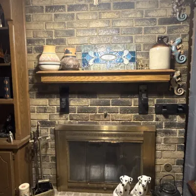 Sale Photo Thumbnail #49: Brick fireplace hearth displaying various home decor items, including Southwestern-style pottery, stained glass panel, stoneware jug, ceramic dalmatian figurines, and brass tools.
