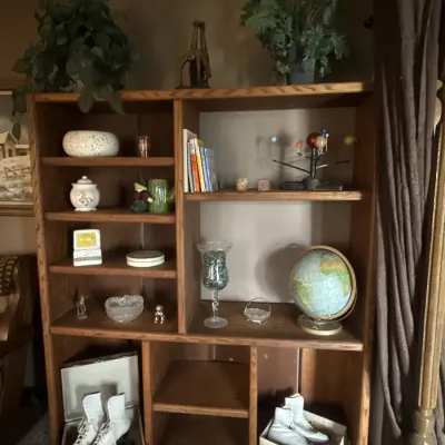 Sale Photo Thumbnail #58: Large wooden bookcase display unit filled with decor, books, a vintage globe, an orrery model, and two pairs of vintage ice skates on the bottom shelf.