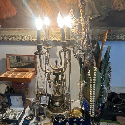 Sale Photo Thumbnail #120: Eclectic collection of costume jewelry, watches, and decorative items displayed around a four-light candelabra lamp and an ornate halberd-style accent piece.