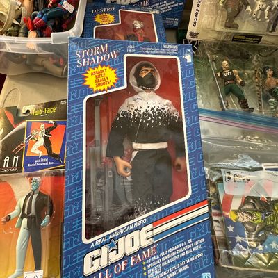 Sale Photo Thumbnail #53: Vintage G.I. Joe Hall of Fame Storm Shadow 12-inch action figure in original box, displayed alongside a carded Kenner Batman: The Animated Series Two-Face figure and other collectibles.