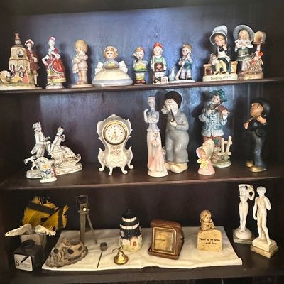 Sale Photo Thumbnail #103: Collection of vintage porcelain and ceramic figurines, small clocks, and decorative knick-knacks displayed on wooden shelf units.