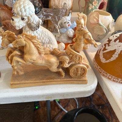Sale Photo Thumbnail #61: Vintage carved resin Roman chariot figurine with horses, displayed alongside a ceramic poodle and other decorative collectibles.