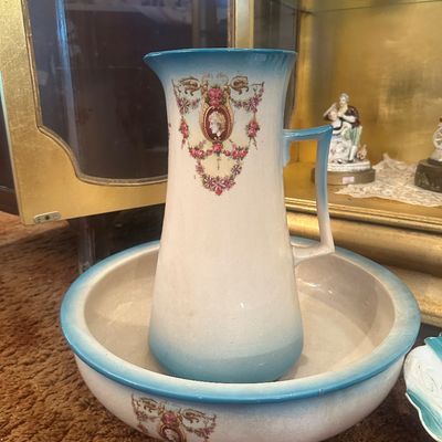 Sale Photo Thumbnail #98: Antique porcelain wash basin and pitcher set, featuring blue-rimmed edges, floral garlands, and a classic cameo profile medallion.
