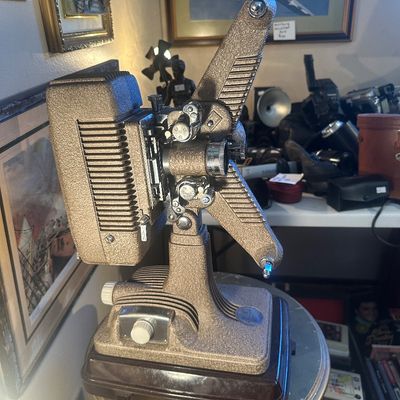Sale Photo Thumbnail #89: Vintage Keystone 8mm movie projector with a bronze-tone crinkle finish, mounted on a solid base, circa 1950s.