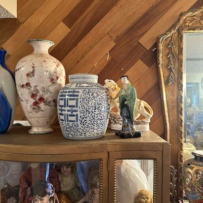 Sale Photo Thumbnail #2: Assorted ceramic decor atop a glass display cabinet, including a floral vase, blue-and-white ginger jar, tiger figurine, and Asian-style geisha statuette.