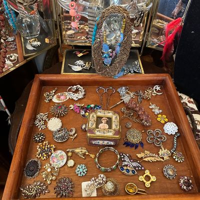 Sale Photo Thumbnail #10: Wooden display tray filled with assorted vintage costume jewelry, including rhinestone brooches, beaded pins, a small framed trinket box, and decorative hairpins.