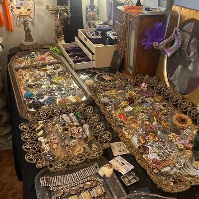 Sale Photo Thumbnail #106: Large collection of vintage costume jewelry, including brooches, necklaces, and earrings displayed on mirrored trays and in wooden jewelry boxes.
