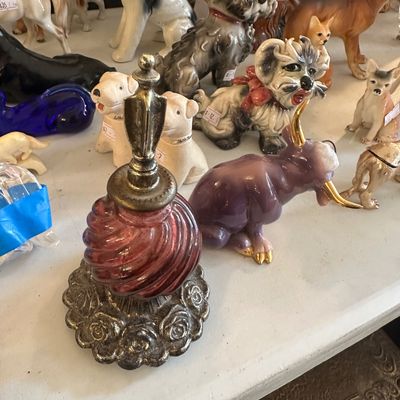 Sale Photo Thumbnail #60: Vintage swirl cranberry glass decanter with ornate metal base and stopper, displayed alongside a collection of ceramic animal figurines.