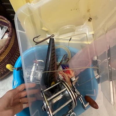 Sale Photo Thumbnail #70: Assorted vintage fishing gear stored in a clear plastic tote and blue tub, including conventional reels, large lures, and leaders.