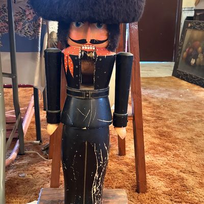 Sale Photo Thumbnail #35: Vintage large wooden floor-standing nutcracker guard figure with a faux fur hat, showing visible wear and paint loss to the body.