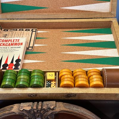 Sale Photo Thumbnail #39: Vintage backgammon game set with cork playing field, green and butterscotch Bakelite-style checkers, leather dice cups, dice, and instruction booklet.