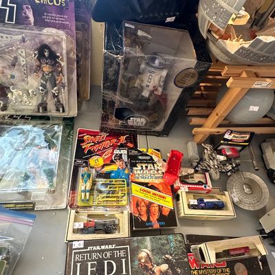 Sale Photo Thumbnail #48: Collection of vintage pop culture toys and collectibles, including packaged KISS action figures, Star Wars books and R2-D2 figure, a Street Fighter II action figure, and die-cast vehicles.
