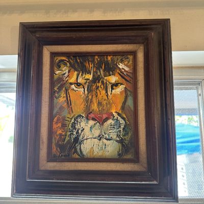 Sale Photo Thumbnail #59: Framed mid-century oil painting depicting a lion's face, signed by the artist in the lower corner. Housed in a dark wood frame with a linen mat border.