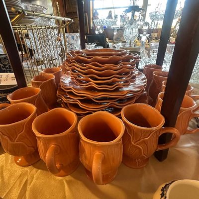 Sale Photo Thumbnail #113: Vintage orange ceramic dinnerware set featuring cabbage leaf-style mugs, bowls, and stacked wavy-edge plates.