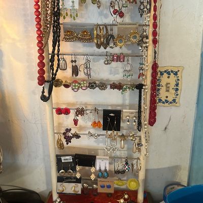 Sale Photo Thumbnail #108: Multi-tier standing rack filled with various vintage and contemporary costume jewelry, including dangling earrings, beaded necklaces, and brooches.
