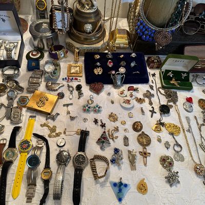 Sale Photo Thumbnail #21: Large assortment of vintage costume jewelry, wristwatches, brooches, necklaces, and small trinket boxes displayed on a table.