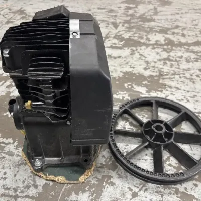 Sale Photo Thumbnail #107: Black single-cylinder air compressor pump motor with attached plastic belt guard and accompanying multi-spoke flywheel.