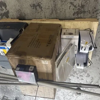 Sale Photo Thumbnail #57: Bulk lot of mixed household goods on a wooden pallet, including boxed Kichler lighting fixtures, air filters, curtain rods, and small electronics.