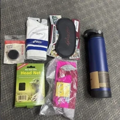 Sale Photo Thumbnail #37: Assortment of new personal accessories and gear, including Asics crew socks, an Ed Hardy sleep mask, a Coghlan's head net, a blue water bottle, and packaged socks.