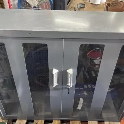 Sale Photo Thumbnail #110: Gray metal industrial storage cabinet by Durham featuring double glass-windowed doors with combination locks and key access.