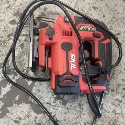 Sale Photo Thumbnail #155: Red and black Skil corded jigsaw with attached blade and power cord, showing light signs of use.