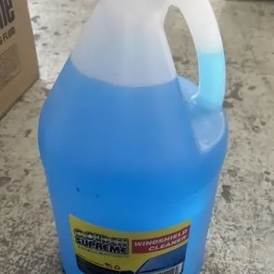 Sale Photo Thumbnail #18: One-gallon jug of Golden Supreme windshield cleaner, partially filled.