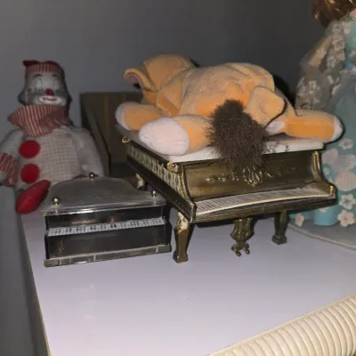 Sale Photo Thumbnail #17: Collection of vintage collectibles including two miniature piano music boxes, a small lion plush toy, and a vintage clown doll.