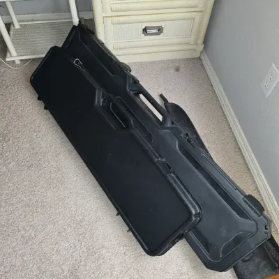 Sale Photo Thumbnail #19: Pair of black hard-shell rifle or firearm transport cases set on carpet next to bedroom furniture.