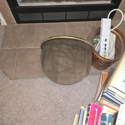 Sale Photo Thumbnail #41: Protective face shield visor sitting on the floor in front of a fireplace, alongside a copper pot holding a power strip.