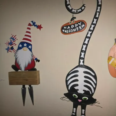 Sale Photo Thumbnail #80: Whimsical holiday metal garden stakes, including a patriotic American gnome and a Halloween skeleton black cat with a hanging 'Happy Halloween' sign.
