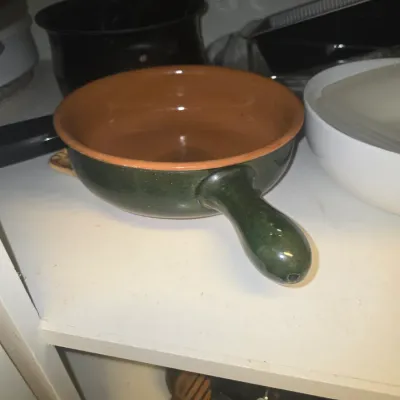 Sale Photo Thumbnail #112: Glazed terracotta pan featuring a dark green exterior, terracotta interior, and a short side handle.
