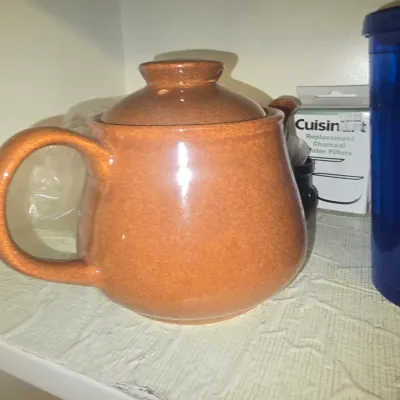 Sale Photo Thumbnail #117: Terracotta glazed ceramic teapot with matching lid, displayed on a cabinet shelf alongside various kitchen supplies.