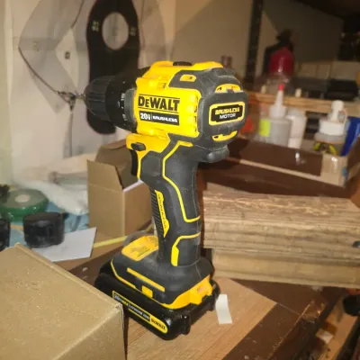 Sale Photo Thumbnail #71: DeWalt 20V Max brushless cordless drill with attached battery pack resting on a workbench.