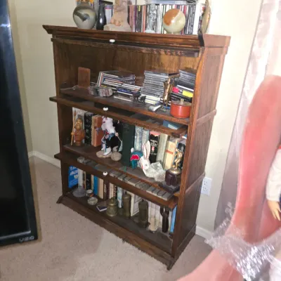 Sale Photo Thumbnail #35: Four-tier dark oak barrister bookcase filled with books, CDs, and various collectibles.
