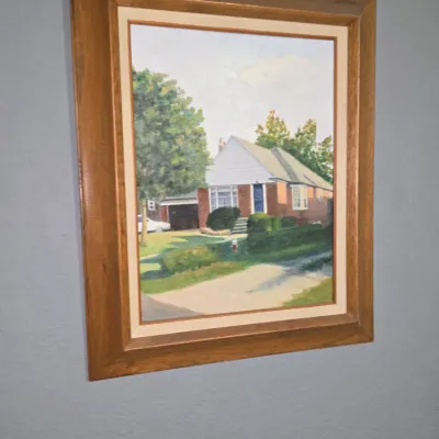Sale Photo Thumbnail #5: Framed oil painting depicting a suburban home and landscape, set in a thick bevel-edged wood frame.